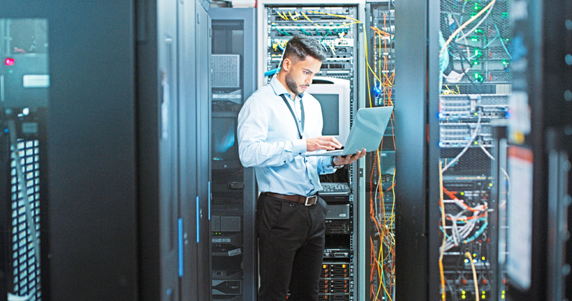 Shot of a young male engineer using his laptop in a server room